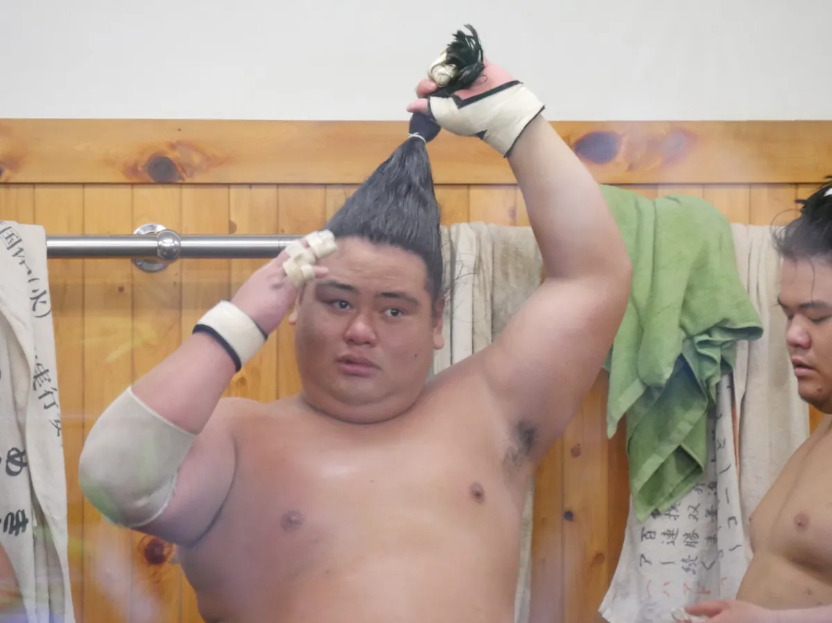 A sumo wrestler ties his topknot at a Tokyo training stable